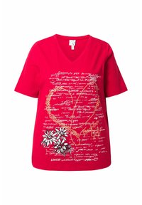 Camiseta de algodón roja con escote en V, que presenta gráficos florales, escritura a mano y acentos dorados. Manga corta y un ajuste relajado.