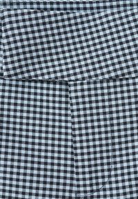 Schwarz-weiß kariertes Gingham-Gewebe mit einem kleinen Karo-Muster und einer sichtbaren Naht, die horizontal durch die Mitte verläuft.
