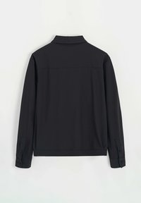 Chemise noire à manches longues avec un col, des poignets boutonnés, une texture lisse et un design simple au dos sans coutures ni motifs visibles.