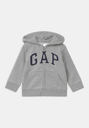 Sweat à capuche gris pour enfant avec fermeture éclair, poches avant et lettres "GAP" bleu marine sur la poitrine, capuche attachée.