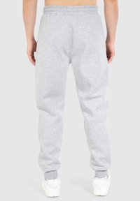 Pantalones de chándal grises hechos de suave felpa, con una cintura y puños elásticos, un ajuste relajado y dos bolsillos traseros.