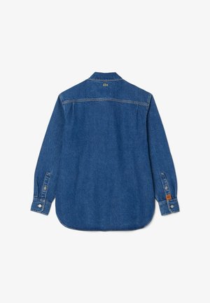 Tumši zila džinsu krekls ar garām piedurknēm, pogu aizdare uz piedurknēm un noapaļotu apakšmalu. Lacoste logo uz muguras netālu no apkakles.