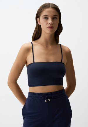 Navyblauwe cropped top met dunne verstelbare bandjes, een zachte stof en een rechte halslijn. Gepaard met bijpassende hoge taille broek.