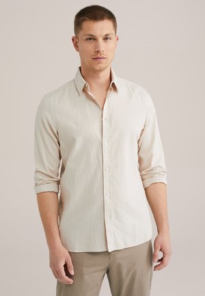 Camisa de manga larga en beige claro, hecha de tela de lino, con un cuello estándar, cierre de botones y puños con vuelta.
