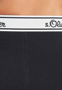 Black underwear featuring a wide elastic waistband with black and white stripes, displaying the brand name "s.Oliver" in black lettering.