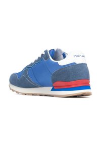 Baskets bleues avec une combinaison de textures lisses et en daim, lacets blancs, un accent rouge et bleu au niveau du talon et une semelle beige.