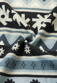 Strickstoff mit einem geometrischen Design und abwechselnden Schneeflockenmotiven in Marineblau, Hellblau und Creme, die ein strukturiertes Muster erzeugen.