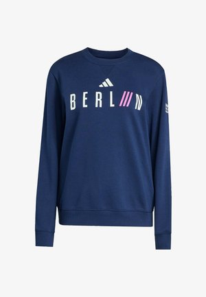 Navyblauwe sweatshirt met lange mouwen met de tekst "BERLIN", roze diagonale lijnen en het Adidas-logo op de borst, en witte tekst op de rechter mouw.