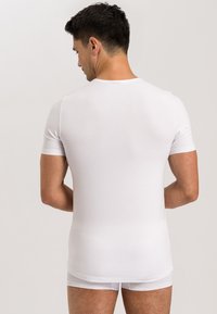 Bílý tričko s krátkým rukávem vyrobené z hladkého materiálu, s klasickým kulatým výstřihem a přiléhavým střihem, z pohledu zezadu.