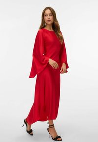 Sarkans maksi kleita ar garām, izplūdušām piedurknēm un noapaļotu dekoltē. Izgatavota no gludas, vieglas auduma ar plūstošu siluetu.