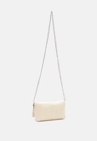 Pochette de couleur crème avec une texture lisse, dotée d'une bandoulière en chaîne argentée et d'une forme rectangulaire simple.