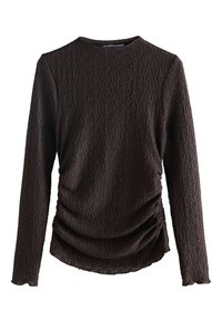 Haut marron à manches longues avec un motif texturé et un détail froncé à la taille. Présente un col rond et des poignets élastiqués.
