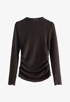 Bruine top met lange mouwen, een gestructureerd patroon en een geplooid detail bij de taille. Heeft een ronde halslijn en elastische manchetten.