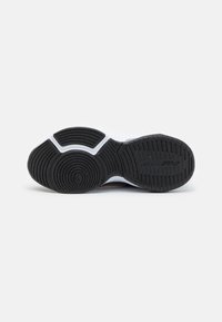 Černá gumová podrážka s texturovanými grip vzory. Obsahuje bílou mezivrstvu a šedé akcenty. Zakřivené a ploché části pro stabilitu.