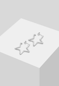 Orecchini a forma di stella in argento con un design in fil wire semplice e una finitura lucida, che mette in risalto linee morbide e uno stile minimalista.