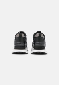 Czarne sneakersy z połączeniem teksturowanej skóry i siateczki. Posiadają czarno-białą podeszwę, pętelkę na pięcie oraz subtelne szare akcenty.