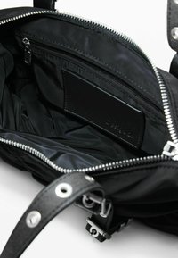 Sac à main noir avec fermeture éclair, intérieur en nylon, accents en cuir et petite poche zippée. Éléments en métal argenté.
