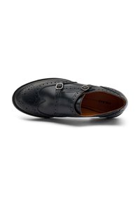Zapato de vestir de cuero negro con detalles de brogue, correas de doble hebilla, punta redondeada, superficie lisa y un forro interior marrón en contraste.