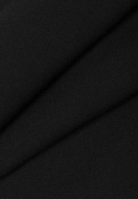 Gros plan sur un tissu noir plié montrant une texture à tissage serré et une surface douce et lisse.