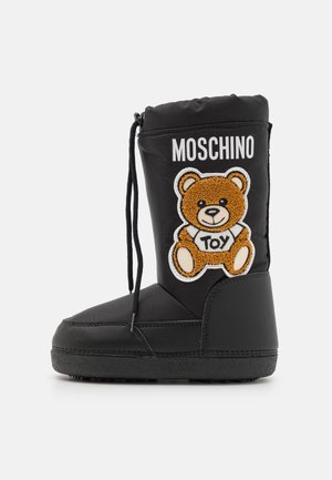 Botte noire imperméable avec doublure en polaire, décorée d'un patch ours en peluche et du texte "MOSCHINO". Semelle en caoutchouc avec bout arrondi et fermeture à lacets.