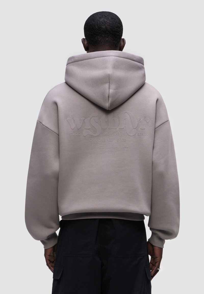 Felpa grigia oversized con cappuccio, con un logo testurizzato sul retro, polsini e orlo a costine, realizzata in un tessuto morbido.