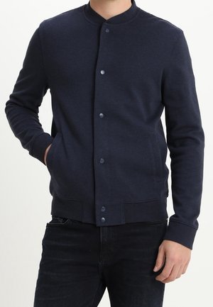 Marineblauwe button-up jas van sweatshirtmateriaal met een ronde kraag, lange mouwen, geribbelde manchetten en zijzakken. Eenvoudig ontwerp.