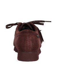 Burgundin suède-kengät, joissa on pyöristetty varvas, koristeelliset nauhat ja teksturoitu pinta. Sisältää pienen logo-yksityiskohdan kannassa.