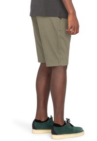 Olivgröna shorts i blandad bomullstyg, med sidfickor, rak passform och matchade med gröna och svarta sneakers.