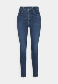 Vaqueros skinny de cintura alta en denim azul oscuro con una textura suave, que cuentan con cinco bolsillos y detalles de costura sutiles.