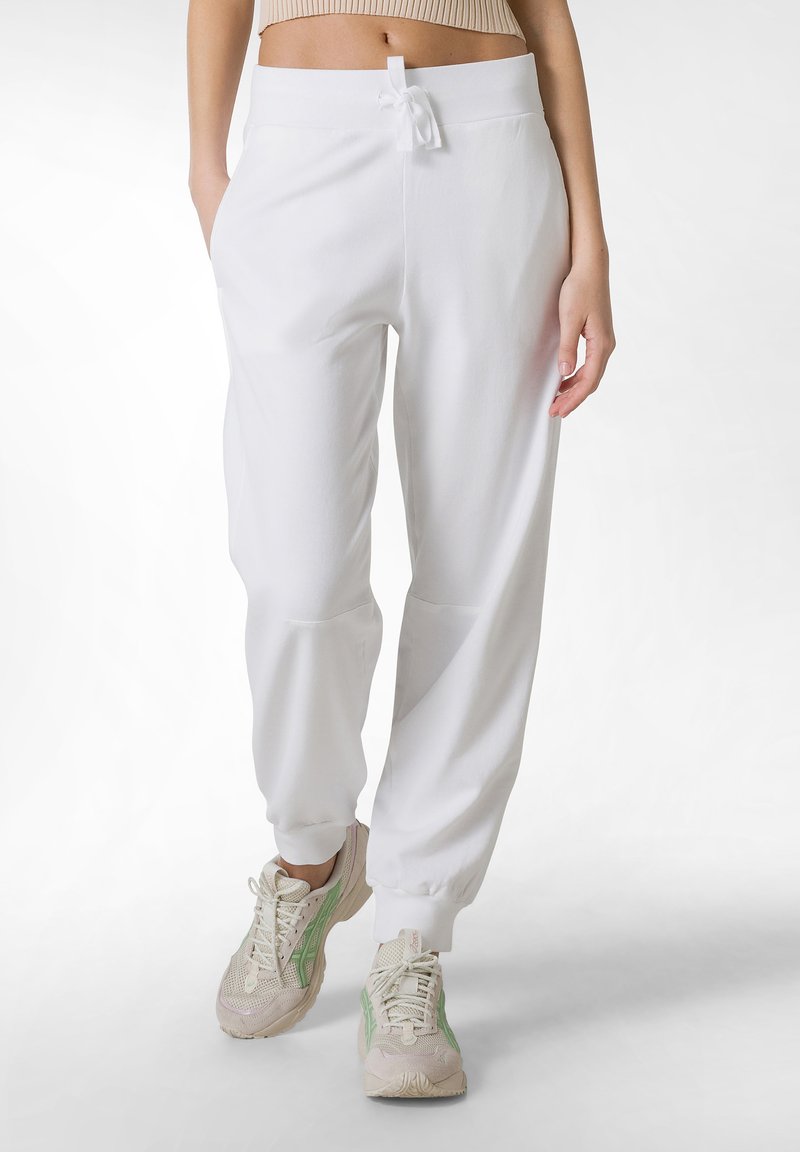 Pantaloni tuta bianchi con cintura elastica regolabile, polsini a gamba affusolata e tasche laterali. Il tessuto è morbido, leggero e con una superficie liscia.