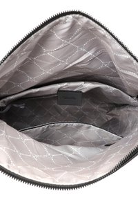 Intérieur d'un sac zippé avec une doublure en tissu gris clair ornée de motifs de points et cercles blancs, comportant une petite poche avec une étiquette "Tamaris".