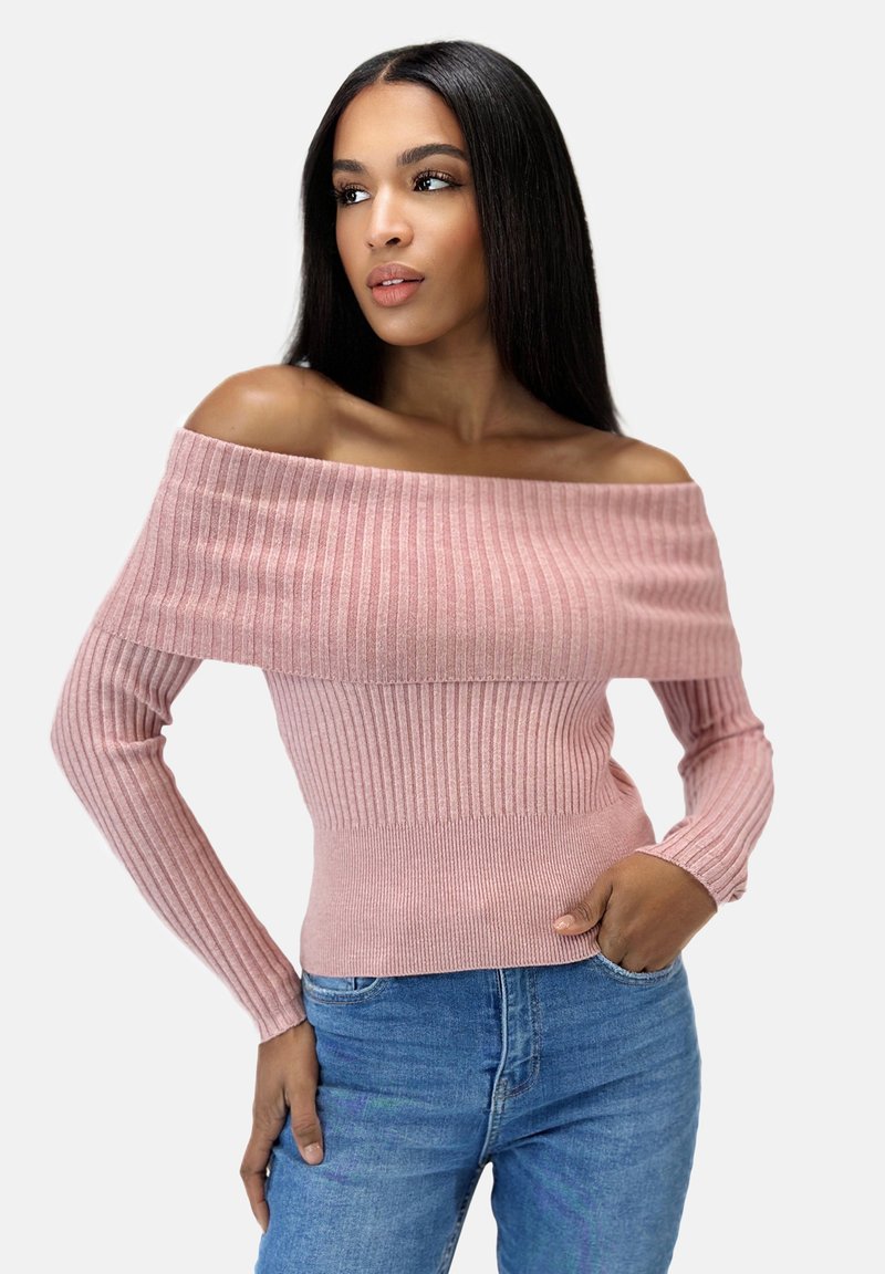 Rosa, rippelstrick Pullover mit schulterfreiem Design, langen Ärmeln und taillierter Passform, kombiniert mit blauen Denim-Jeans.