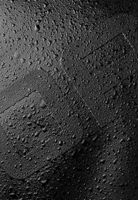 Superficie negra cubierta de gotas de agua, mostrando una textura texturizada con formas geométricas visibles sutilmente integradas en el diseño.