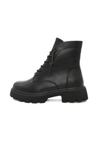 Stivaletti neri in pelle con suola in gomma spessa. Presentano punta rotonda, lacci frontali con occhielli metallici e una texture liscia.