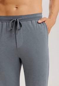 Grijze drawstring broek van zacht, lichtgewicht stof. Met een elastische tailleband en zijzakken, met een gladde, matte textuur.