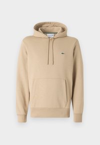 Sweat à capuche beige avec poche kangourou à l'avant, capuche avec cordon de serrage, et petit logo crocodile vert sur le côté gauche de la poitrine.