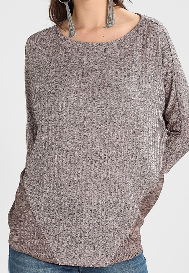 Brun, strukturerad tröja med rundad halsringning och lös passform. Har en geometrisk design vid fållen, ihop med avslappnade blå jeans.