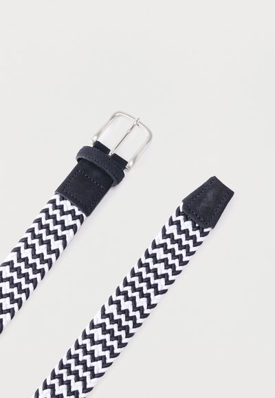 Ζώνη από υφαντό ύφασμα με ασπρόμαυρο ζιγκ-ζαγκ μοτίβο, ασημένια μεταλλική αγκράφα και μαύρα δερμάτινα άκρα σε λευκό φόντο.