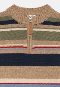 Strikkegenser med halv glidelås i kragen, med horisontale striper i beige, grønn, marineblå, rød og lyseblå. Strukturert stoff.