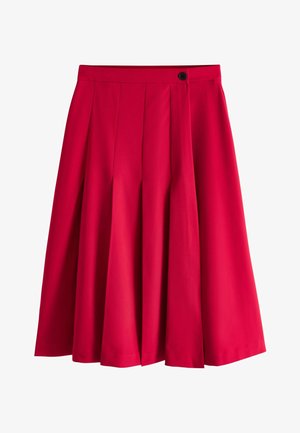 Gonna plissettata rossa al ginocchio con vita alta e chiusura con bottone nero sul lato destro.