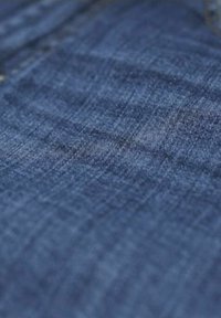 Tela de mezclilla azul oscura con un tejido texturizado, que muestra sutiles variaciones en la tonalidad y un acabado suave. Sin patrones ni acentos visibles.