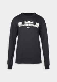 Czarna koszulka z długim rękawem wykonana z bawełny, z białym geometrycznym nadrukiem na wysokości klatki piersiowej oraz małym logo Nike na środku.