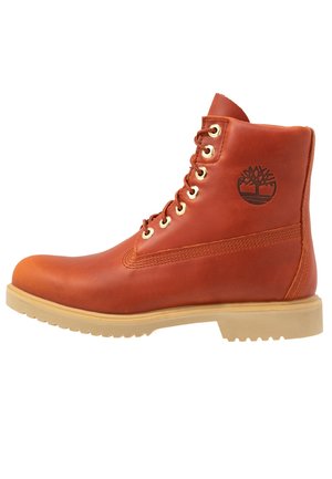 Brązowy skórzany botek sznurowany z beżową podeszwą i logo Timberland na kostce, widok boczny, wytrzymały design do użytku na zewnątrz.