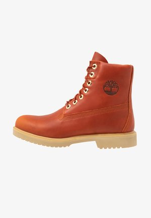 Brązowy skórzany botek sznurowany z beżową podeszwą i logo Timberland na kostce, widok boczny, wytrzymały design do użytku na zewnątrz.