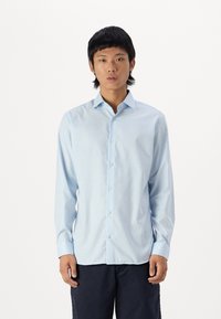 Lichtblauwe langemouwen shirt gemaakt van gladde stof, voorzien van een button-down kraag, een knoopsluiting aan de voorkant en een subtiele ruitpatroon.