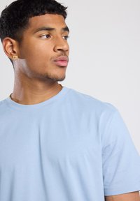 Light blue cotton t-shirt with a crew neckline and short sleeves. Smooth texture, simple design, and minimal stitching details.
