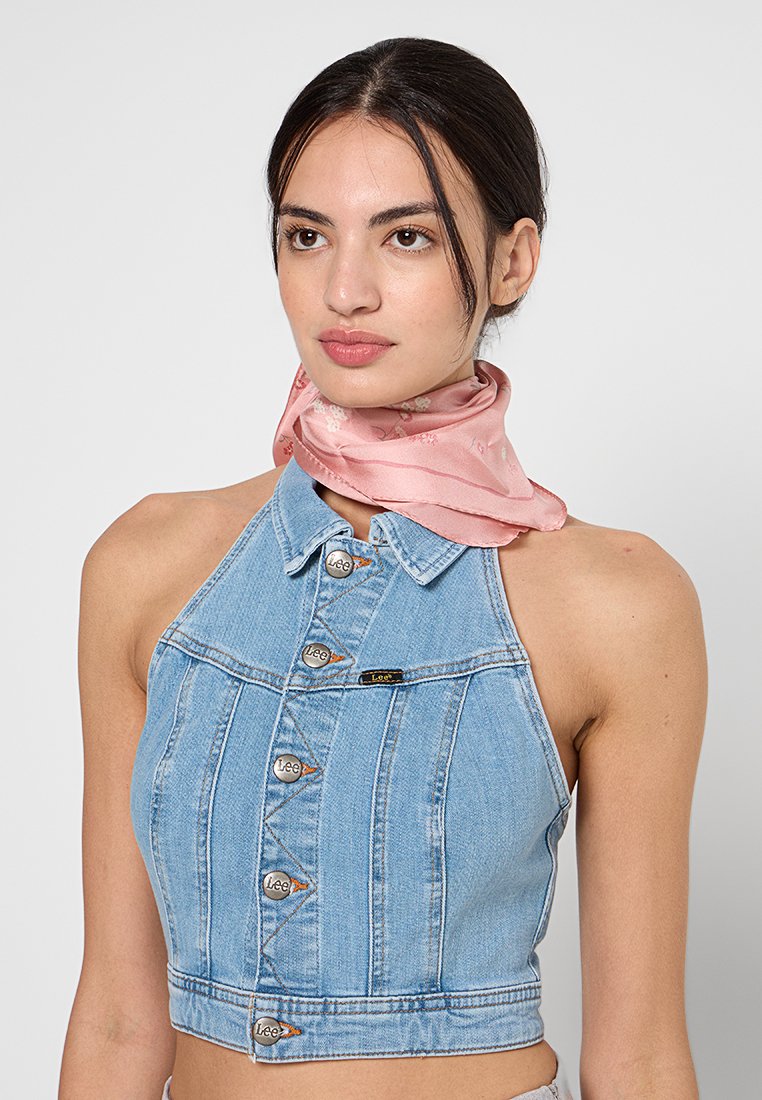 Denim-Halter-Crop-Top mit silberfarbigen Knöpfen, tailliertem Design und einem Etikett mit "Lee." Begleitet von einem rosa Blumen-Seidentuch.