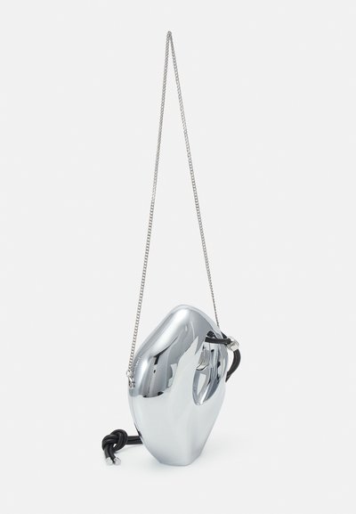 Metallic silver bag with a smooth, sculptural shape, featuring a chain strap and a black cord accent. Reflective surface with a polished finish.