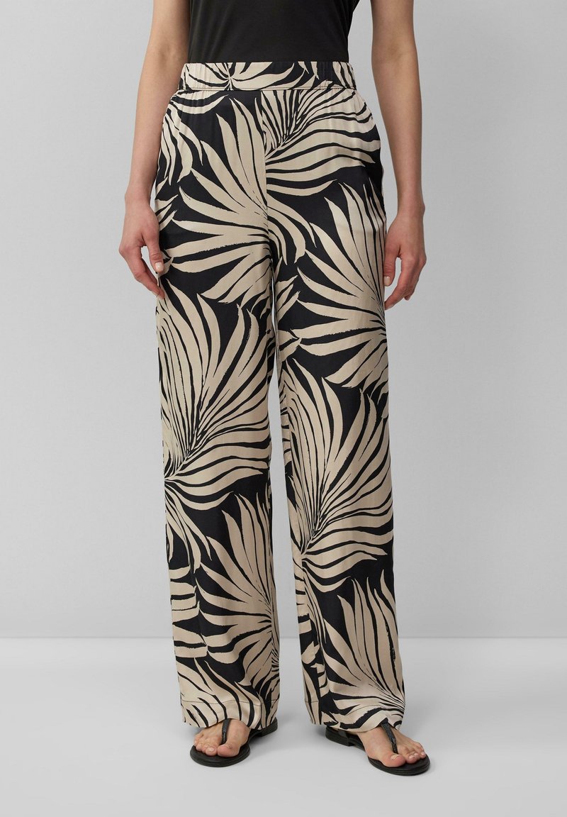 Pantalon à jambes larges en tissu léger, avec un fond noir orné de grands motifs de feuilles beiges. Taille élastique pour le confort.