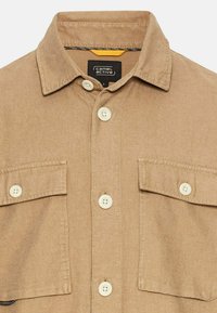 Beige overhemd met knopen en een kraag, twee borstzakken en witte knopen. Gemaakt van gestructureerde stof, met contrasterende stiksels en een label aan de binnenkant.